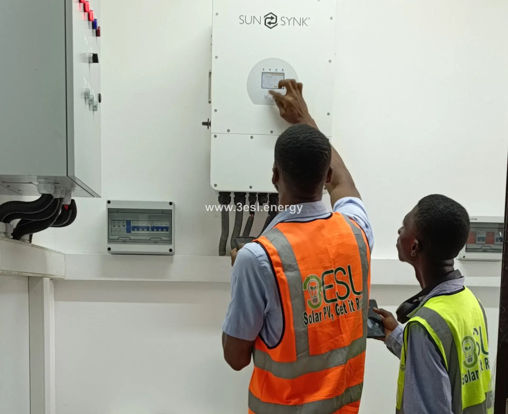 Two 3ESL engineers commissioning a wall-mounted Sunsynk hybrid inverter.