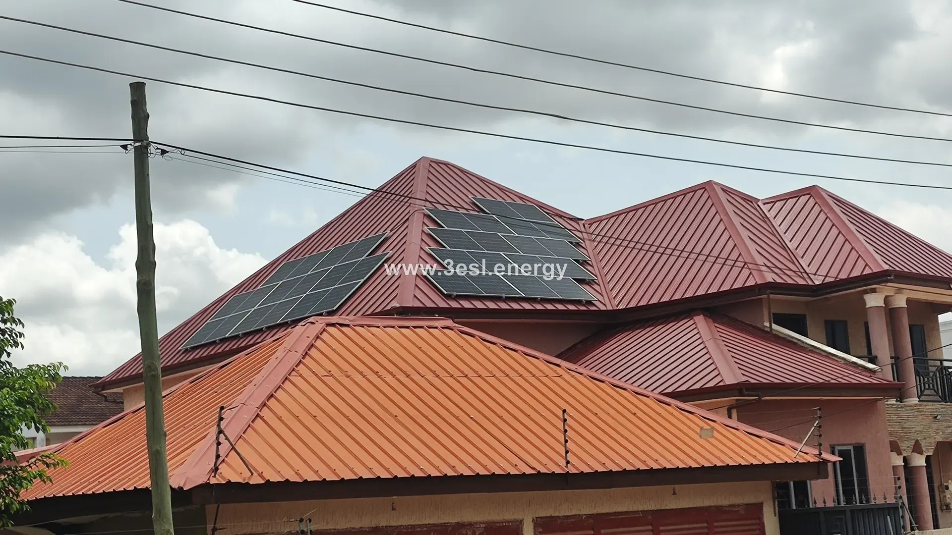 A two-storey family home with a red tiled roof carrying a photovoltaic array.
