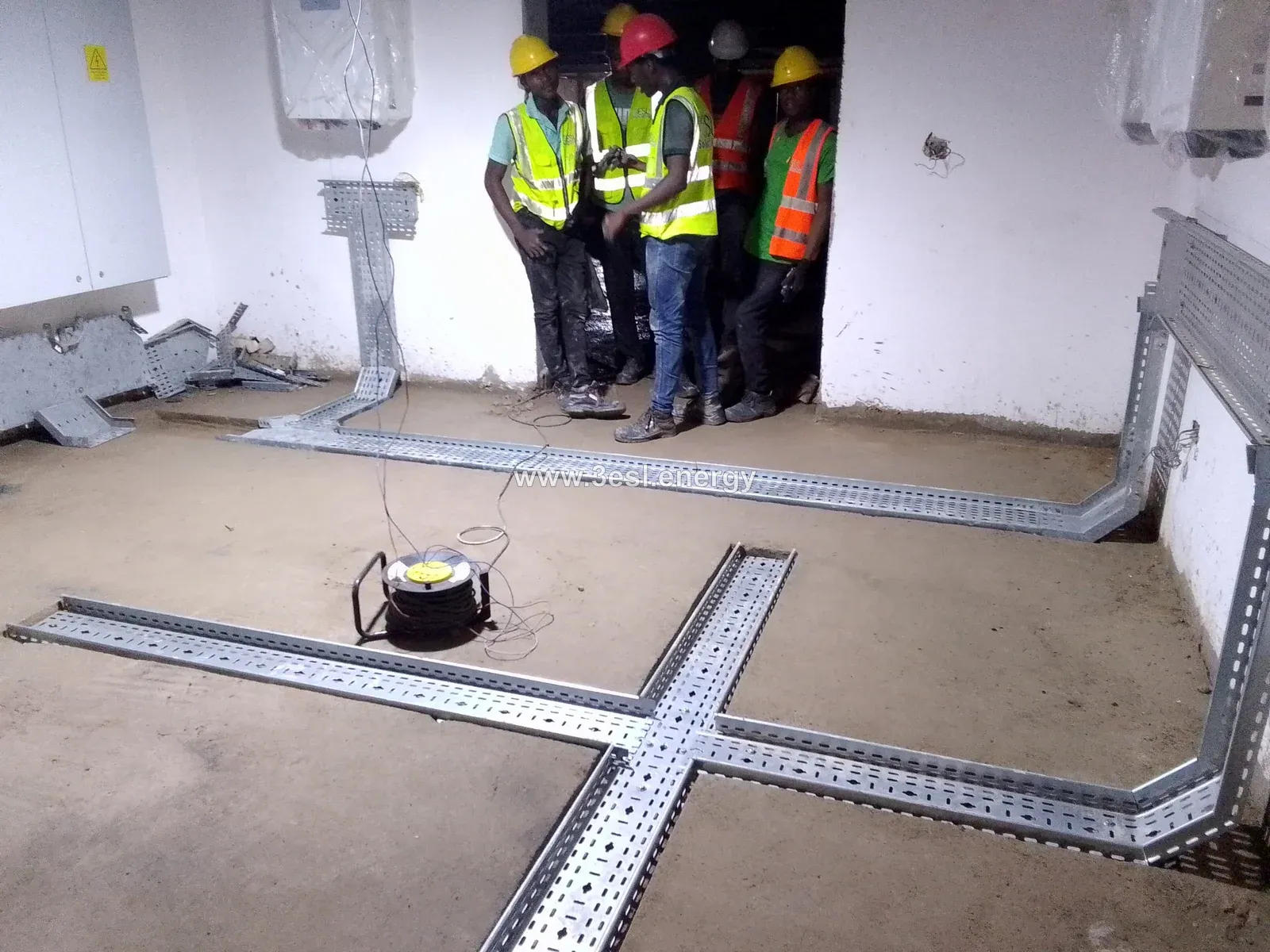 Installation team arranging cable trays inside an industrial solar plant room.