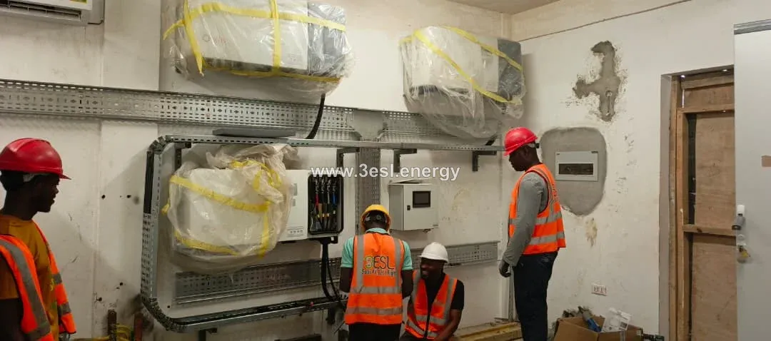 Technicians installing inverters and cable containment in an industrial plant room.