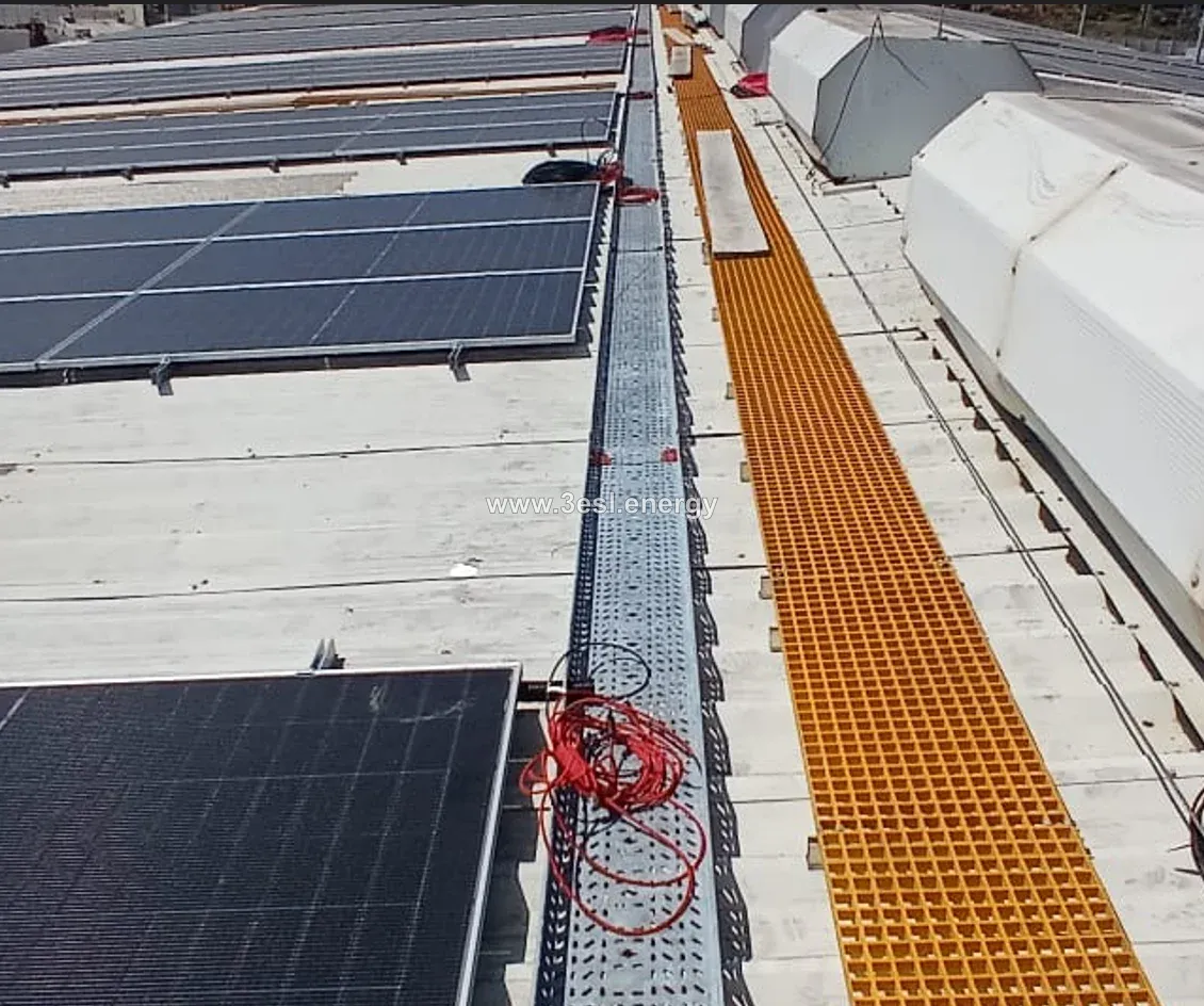 A yellow maintenance walkway and cable tray running beside industrial rooftop solar panels.