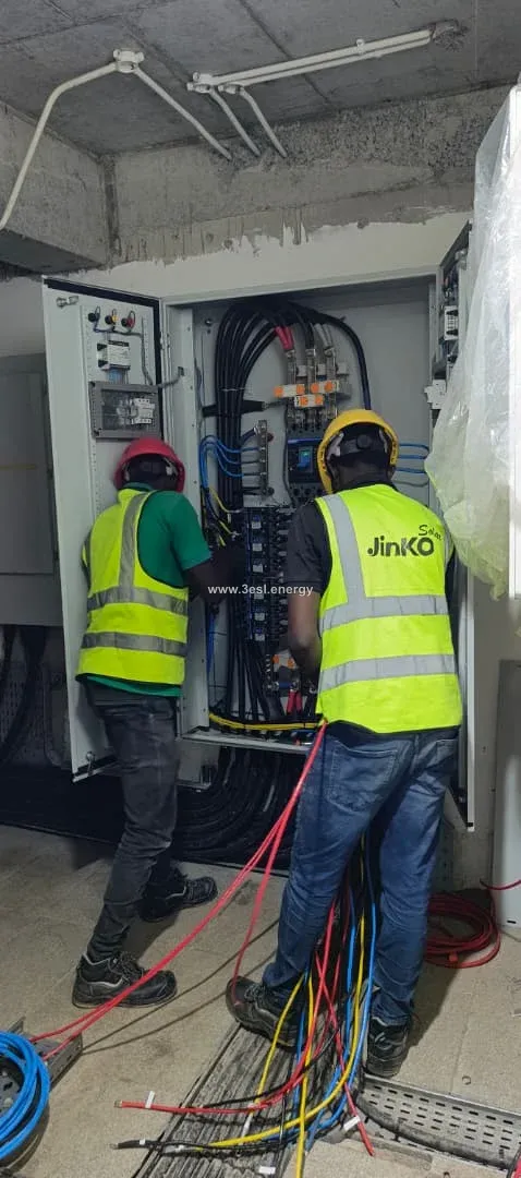 Two technicians wiring an industrial electrical switchboard.