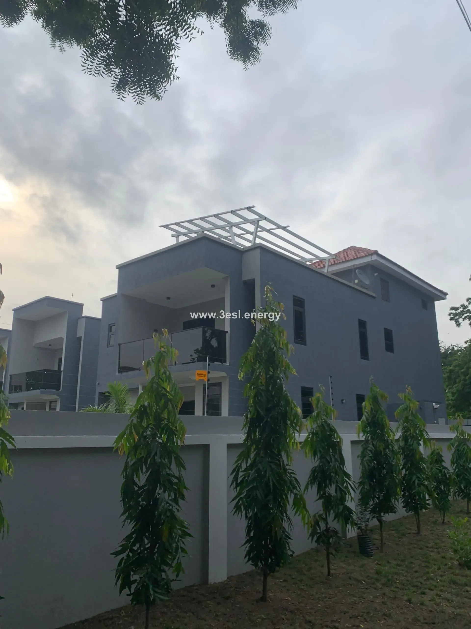 A modern three-storey home with a roof-mounted solar array seen from the garden.