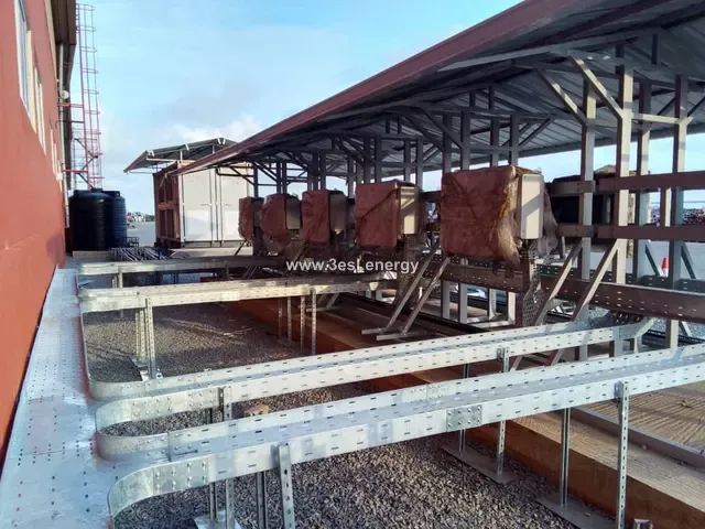 Utility-scale inverters mounted beneath a galvanised cable tray carrying heavy DC cabling.
