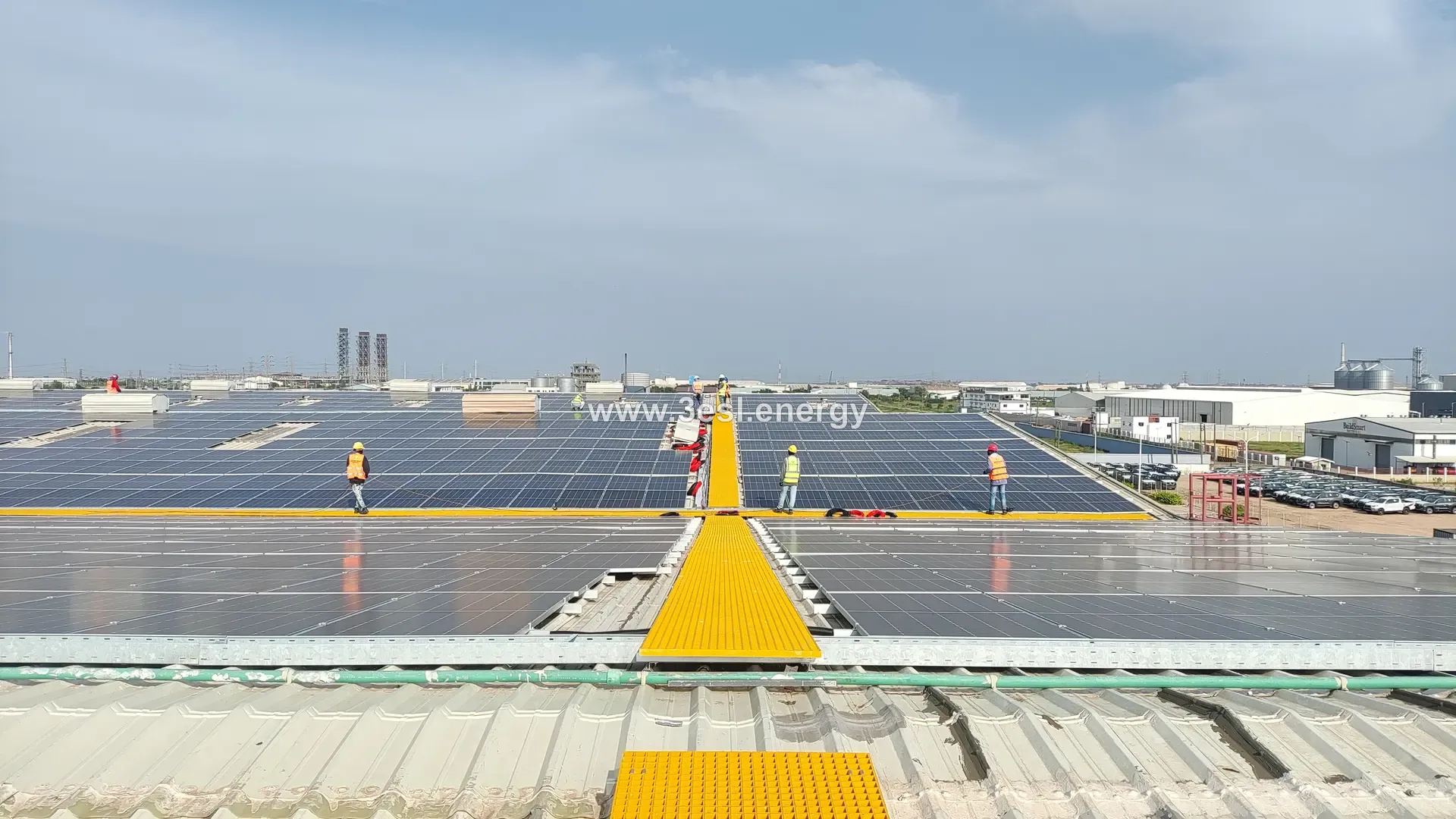 A vast rooftop solar array stretching to the horizon, split by a yellow maintenance walkway.